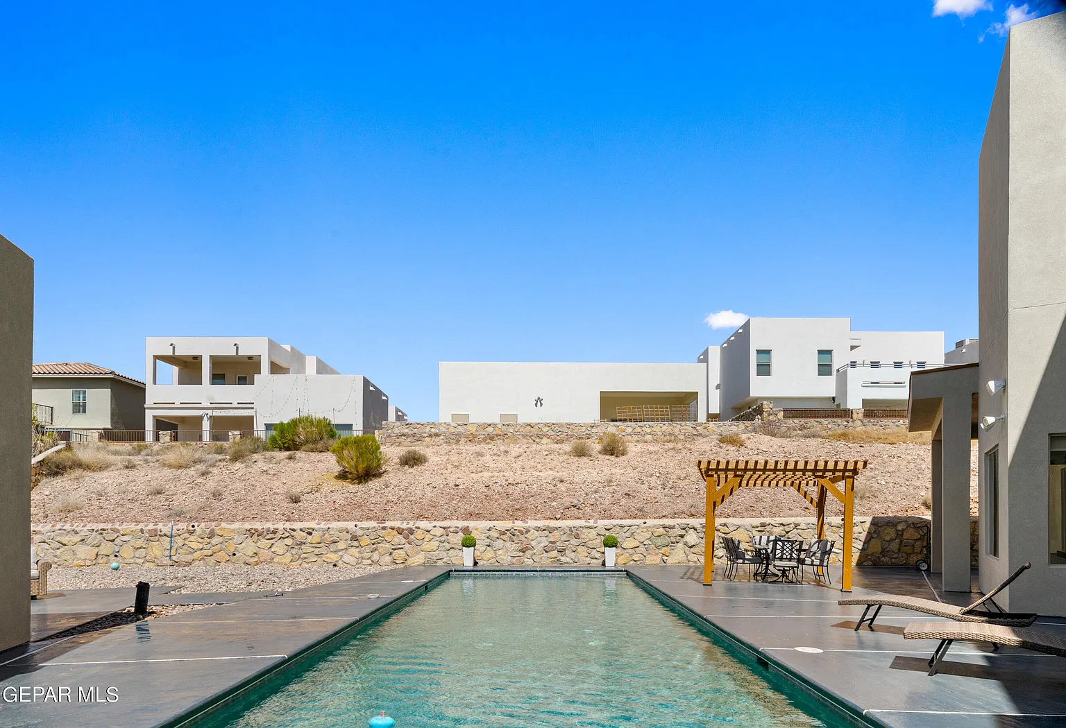 Original photo of the pool with the pergola and outdoor dining area beyond