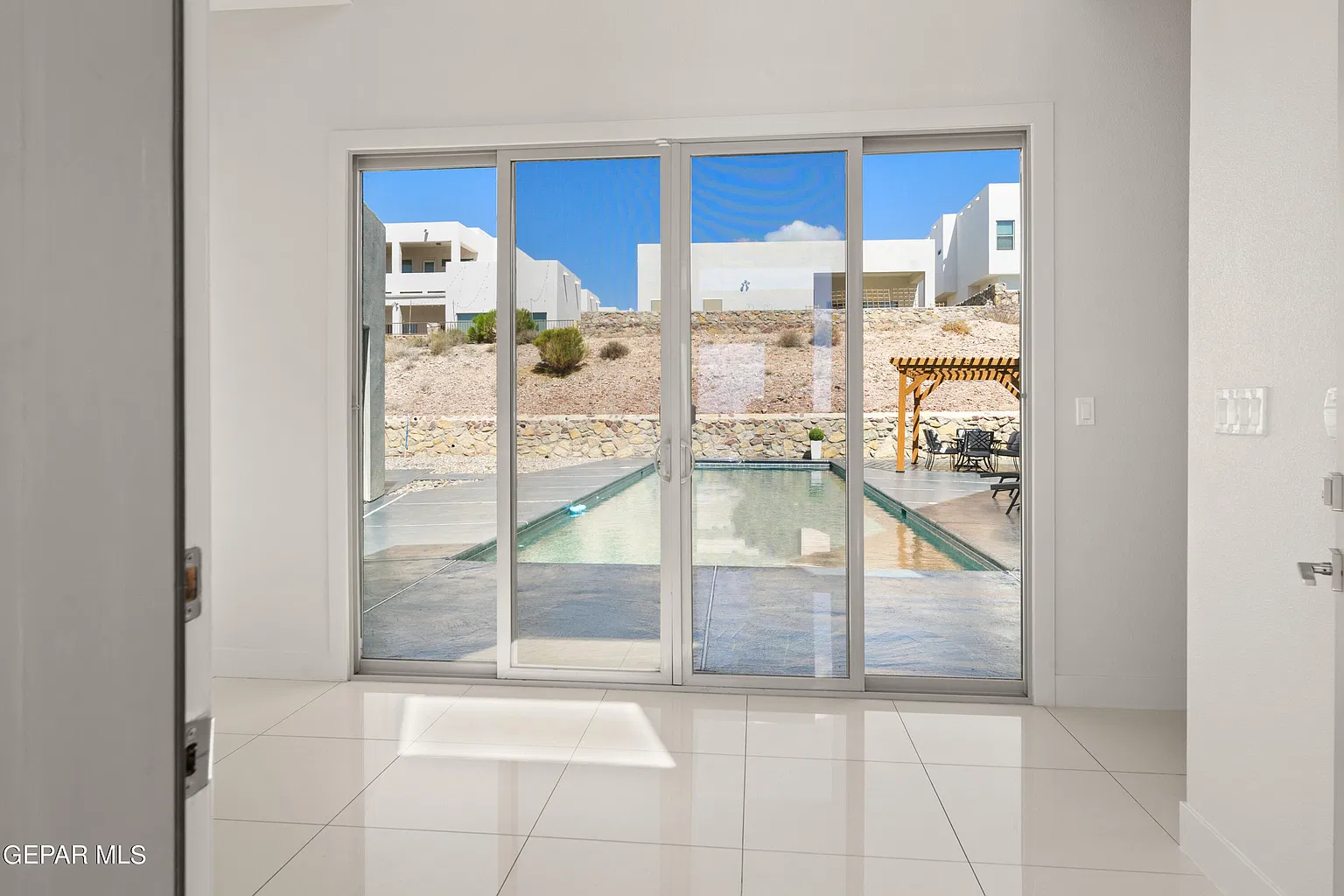 Original photo looking from the living room through the sliding glass doors to the backyard pool